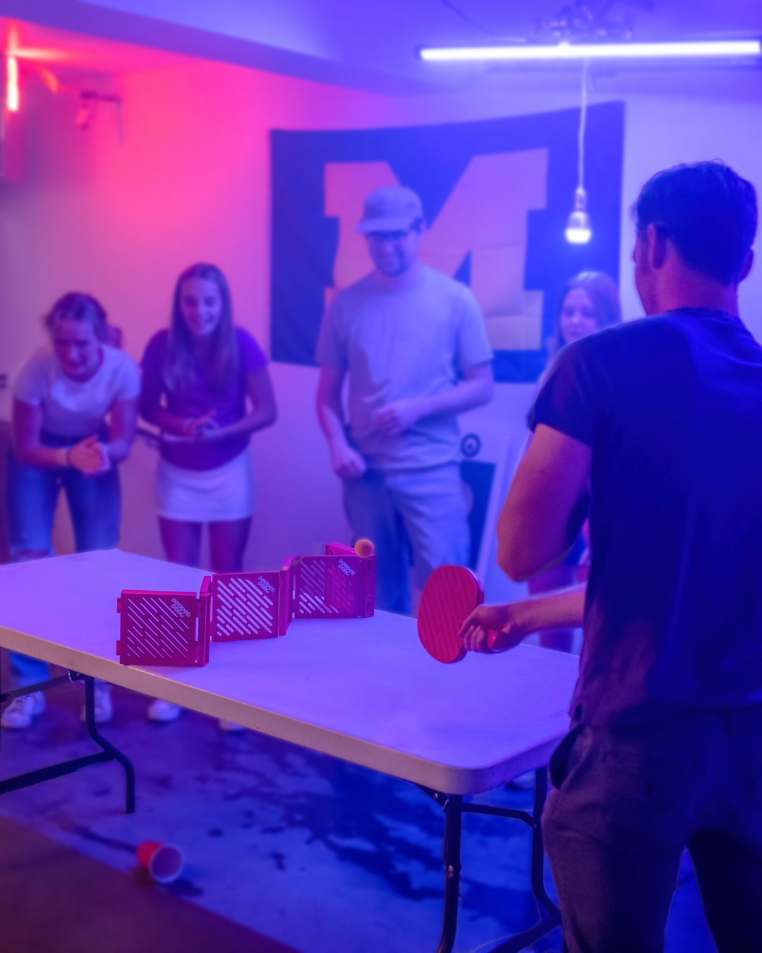 Two players mid-rally over a Pepper Pong net set up in a garage